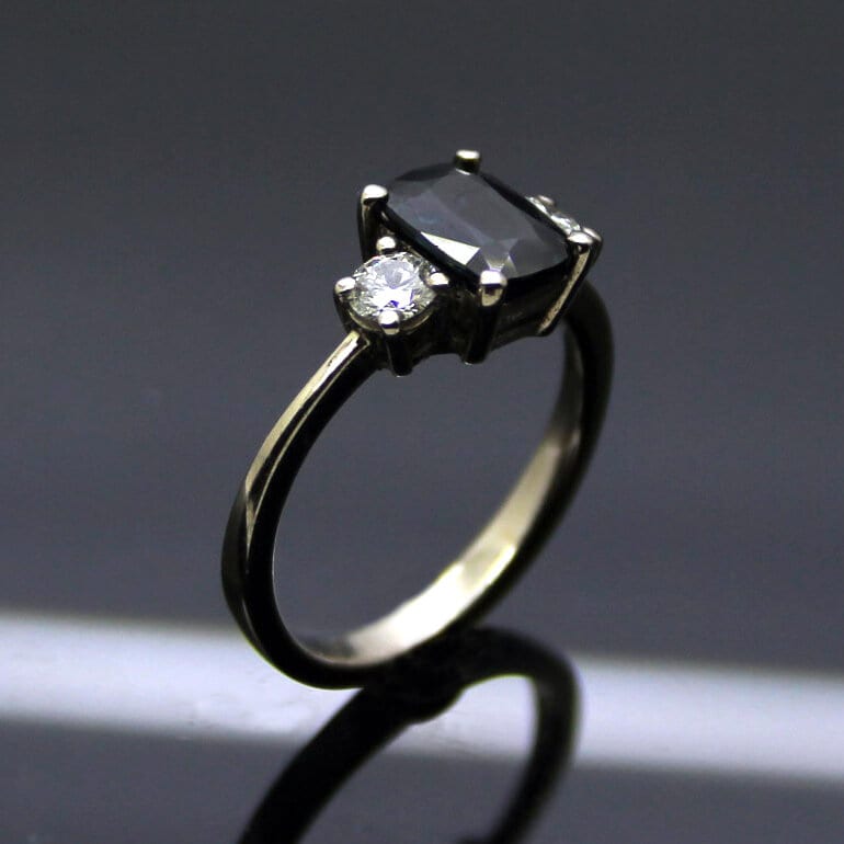 CUSHION CUT SAPPHIRE & PRINCESS CUT DIAMONDS IN 18CT WHITE GOLD TRILOGY ENGAGEMENT RING